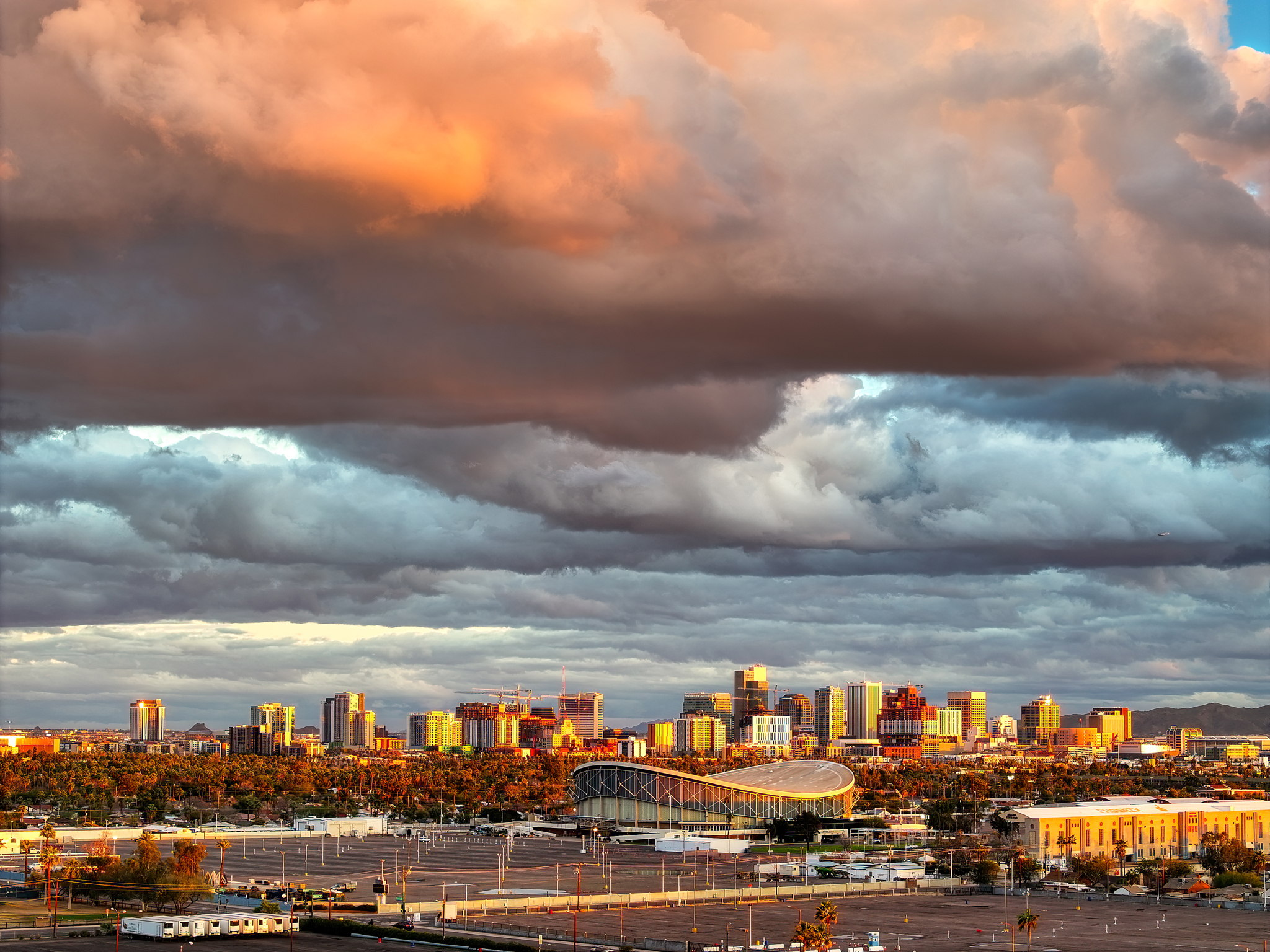 Panoramic aerial view of the Phoenix skyline at sunset, featuring AZ state fairgrounds in the foreground under a dramatic cloudy sky.